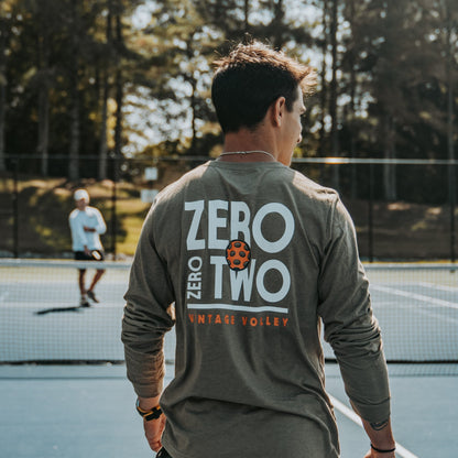 A male pickleball player wearing the Zero Zero Two Vintage Volley Long Sleeve Shirt in Sand. The bold “Zero Zero Two” graphic and comfortable fabric make this shirt ideal for intense games or casual court time. Designed for those who love the sport.